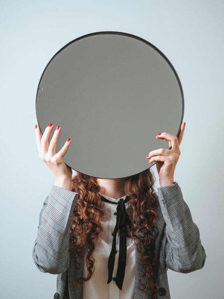 Person holding round mirror over face